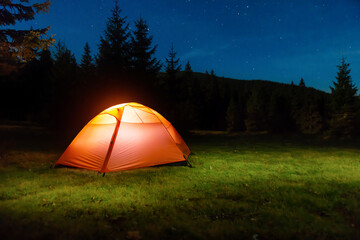 Illuminated tent in night forest © Pavlo Vakhrushev
