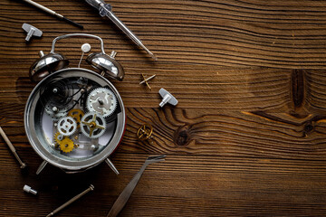 Watchmaker tools near watch mechanism of alarm clock