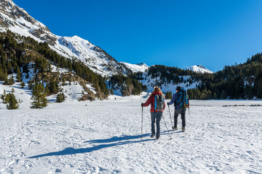 Two people, man and woman, walking with snowshoes and crampons up the mountain. Mountaineering, alpinism. Snowy landscape of the Pyrenees.