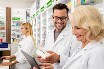 Portrait of two pharmacist working  in drugstore. - obrazy, fototapety, plakaty