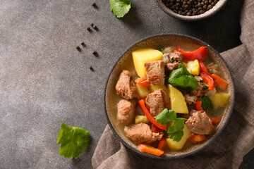 Beef stew with vegetables, potatoes, pepper,carrot in bowl on brown background. European cuisine. Top view.