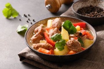 Beef stew with vegetables, potatoes, pepper,carrot in bowl on brown background. European cuisine. Close up.