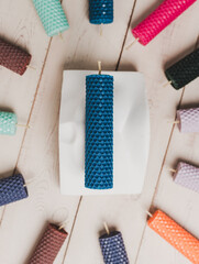 Multicolored beeswax candles with honeycomb texture on a wooden floor.
