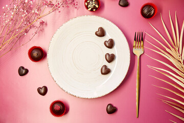 White mock up vintage plate with fork and chocolate hearts. Romantic dinner, Valentines Day concept. Chocolate hearts and decorated sweets