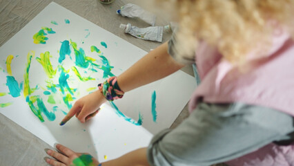 Artist girl shot from above, sitting on the floor using the colors on the sheet. High quality photo