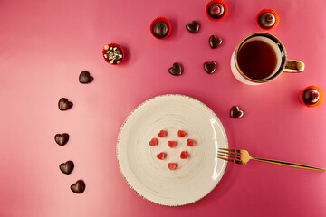 Ice hearts on white vintage plate with fork. Chocolate hearts and decorated sweets. Pink gradient background. Creative romantic dinner, Valentines Day concept. View from above.