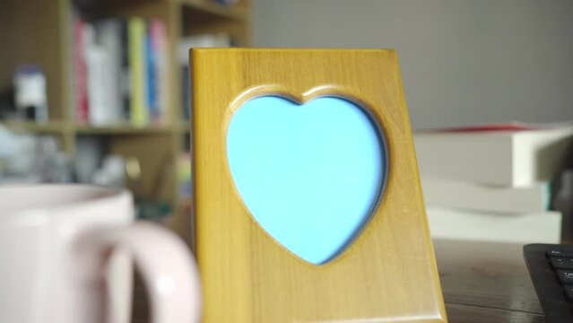 Heart-shaped wooden photo frame on a working table