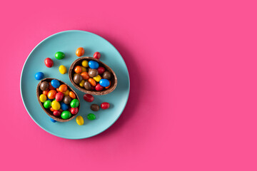 Colorful chocolate Easter eggs on pink background. Top view. Copy space