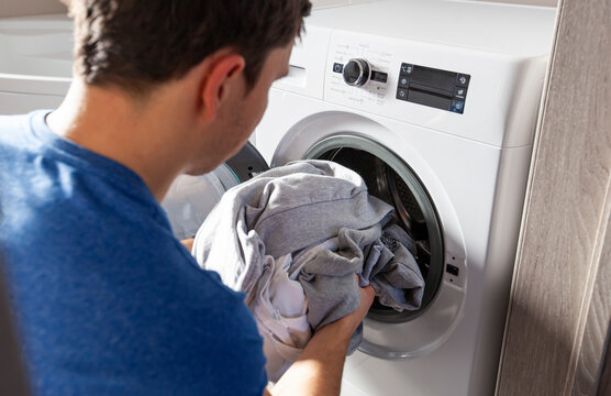 Man loading the washer dryer with clothes