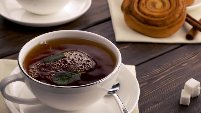 hot black tea is poured into a mug. morning breakfast. Tea has both tonic and soothing properties. Served with sugar, lemon, milk or cream, often accompanies dessert.