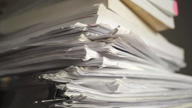 A pile of paper sheets and books on a table