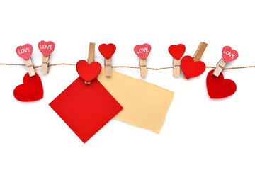 Wooden clothespins with hearts and sheets of blank paper hanging on a linen cord. Concept for valentines day. Greeting card.
