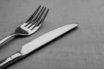 Shiny fork and knife on grey table, closeup