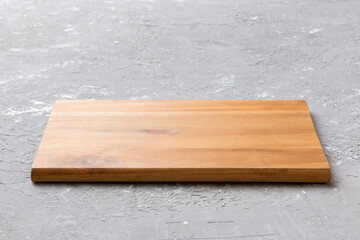 Perspective view of wooden cutting board on cement background. Empty space for your design