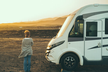Alternative tourist vanlife concept with standing woman in back view near a big camper van...