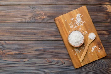 A wooden bowl of salt crystals on a wooden background. Salt in rustic bowls, top view with copy space