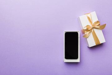 Opened gift box with gold ribbon and smartphone on color background, top view. Blank open box packaging mockup , Template for your design - branding mockup