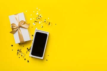 Opened gift box with gold ribbon and smartphone on color background, top view. Blank open box packaging mockup , Template for your design - branding mockup