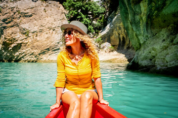 Obraz premium Cute adult tourist woman enjoy outdoor leisure activity sith kayak experience tour on a blue clean water river. Summer holiday vacation and cheerful female people having fun on the boat