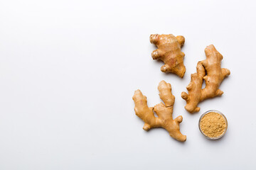 Finely dry Ginger powder in bowl with green leaves isolated on colored background. top view flat lay