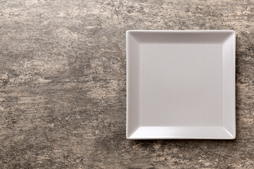 Top view of empty square plate on cement background. Empty space for your design