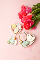 Easter floral background, various gingerbread glazed cookies end decorated with natural botanical elements on pink, flat lay, view from above, blank space for greeting text, banner, flyer, coupon