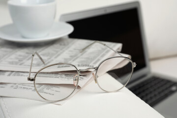 Newspapers, glasses and cup of drink on armrest indoors