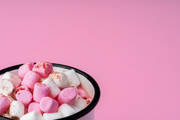 Cup of hot cocoa with marshmallows on pink background