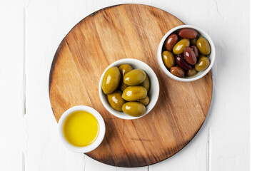 Small bowl with olive oil and olives on white background, top view