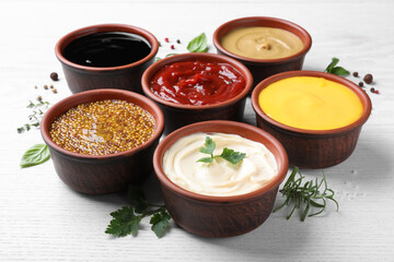 Many different sauces and herbs on white wooden table