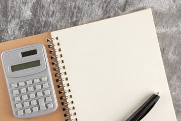 blank notebook, pen and calculator on cement or concrete surface floor. Empty space for business concept copy space.