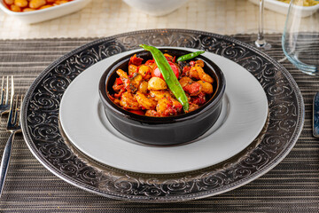 Shrimp stew with tomatoes, garlic and peppers in a black stone bowl