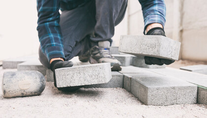 Worker lining paving slabs path