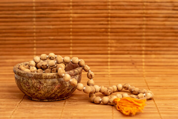 brown bowl with mala beads on wooden background for japa meditation and mindfulness