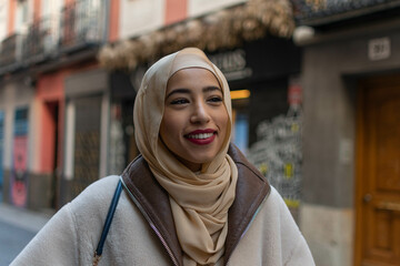 Portrait of young Arabic beautiful woman in traditional headscarf smiling happily to camera. Close...