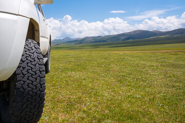 4x4 offroad truck on green mountain valley with mountains and cloudy sky on background . Summer off-road trip. © Adil