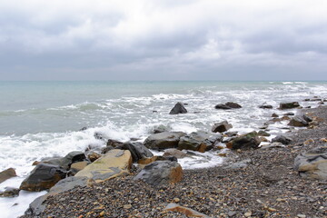 the rocky shore of the undulating sea in cloudy weather