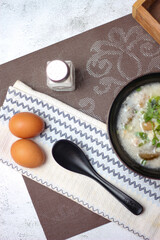 Pork boiled rice with shiitake mushrooms on a black bowl with a spoon on the table.