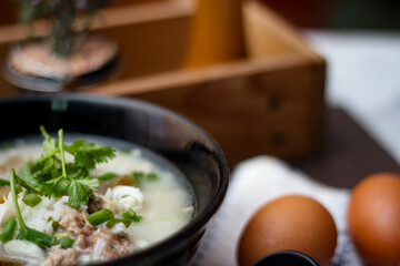 Pork boiled rice with shiitake mushrooms on a black bowl with a spoon on the table.