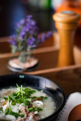 Pork boiled rice with shiitake mushrooms on a black bowl with a spoon on the table.