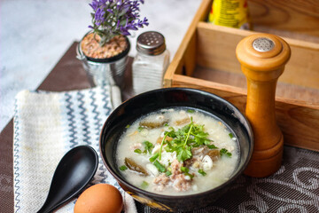 Pork boiled rice with shiitake mushrooms on a black bowl with a spoon on the table.