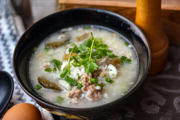 Pork boiled rice with shiitake mushrooms on a black bowl with a spoon on the table.