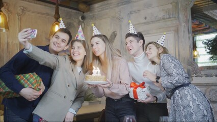 The birthday girl is delighted to celebrate her birthday with her best friends. The girl makes a joint selfie on her phone with her friends