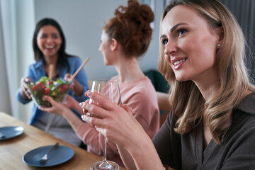 Three female caucasian friends chatting and drinking wine at home.