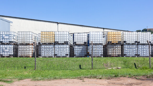 Industrial Chemical Holding Tanks With Metal Cage for safe transportation of liquids stacked outdoors in blue sky