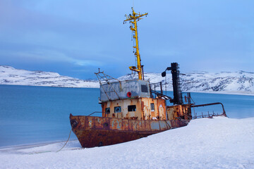 The sea and an abandoned old ship, a boat in the snow. Side view. Winter landscape in Russia, Kola...