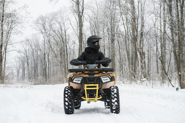 Man on a quad bike in winter background. Portrait of a quadricycle rider in snowy forest