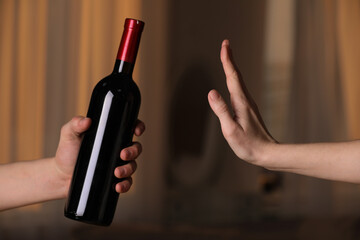 Woman refusing to drink red wine indoors, closeup. Alcohol addiction treatment