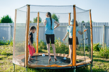 Three girls jumping on a trampoline, girlfriends having fun in the summer in a recreation park on a trampoline