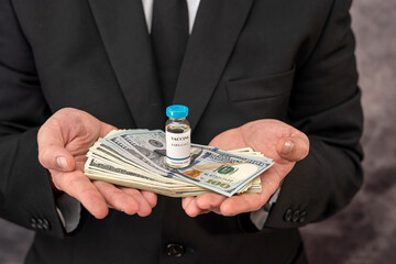 Stylish man with strong hands in a suit carries the vaccine in a jar and dollars for it.